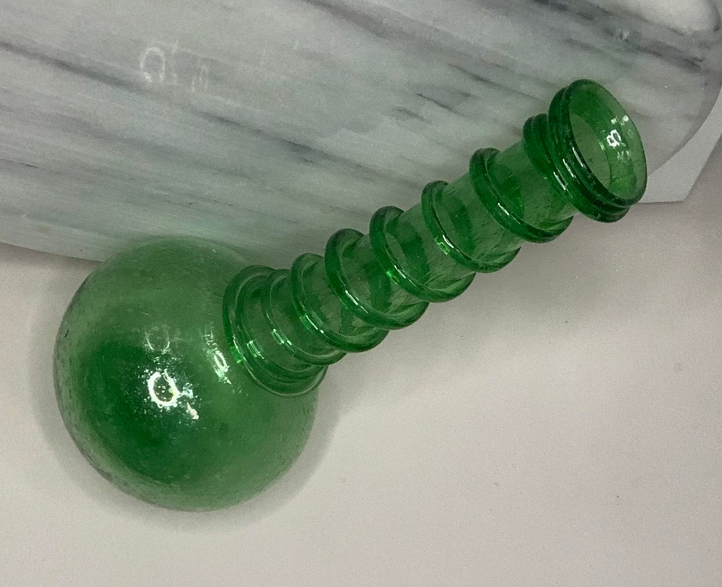Hand-blown emerald green recycled glass bud vase with air bubbles throughout and a spiral decoration along the neck, finished with a pontil mark.
