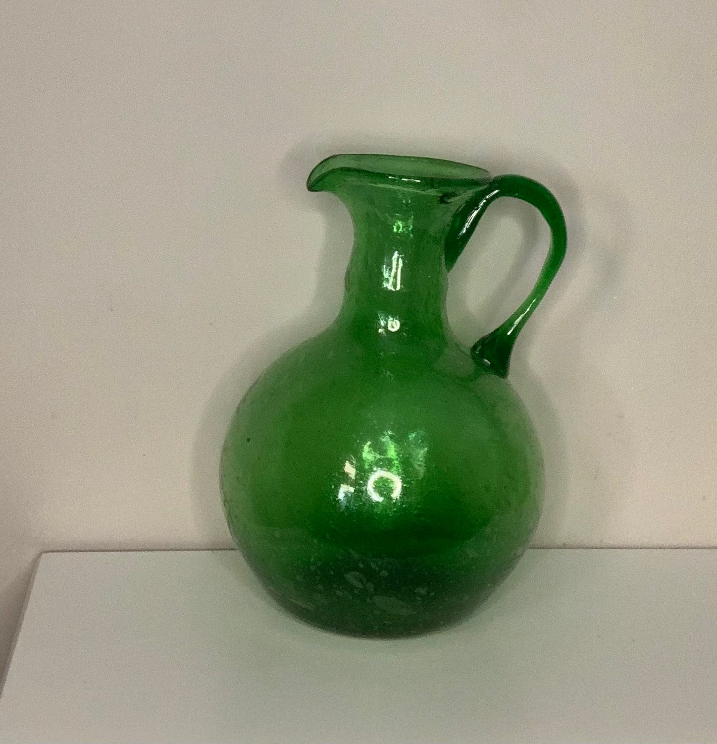 Hand-blown emerald green glass bottle decanter carafe with visible air bubbles throughout and a pontil mark, suitable for use as a vase or decorative piece.