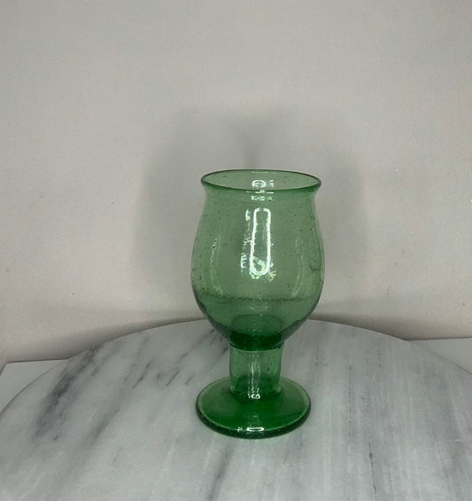 A green glass goblet or tumbler with a wide flared rim and a short stem.