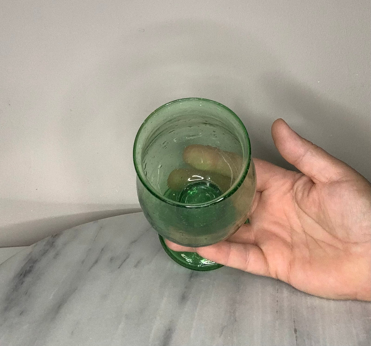 A green recycled glass goblet or tumbler with a wide flared rim and a short stem.