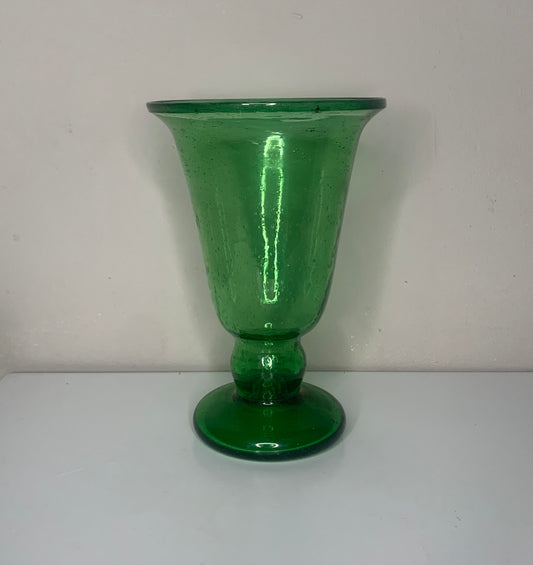 A green glass pedestal glass with a flared rim and a round base.