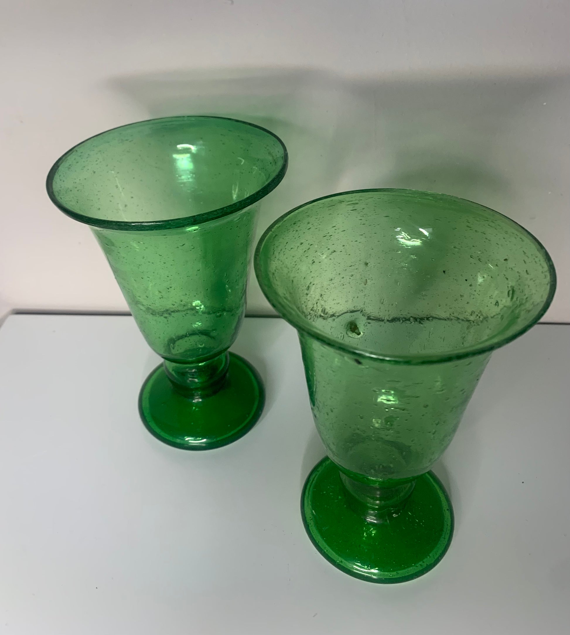 A green glass pedestal glass with a flared rim and a round base.