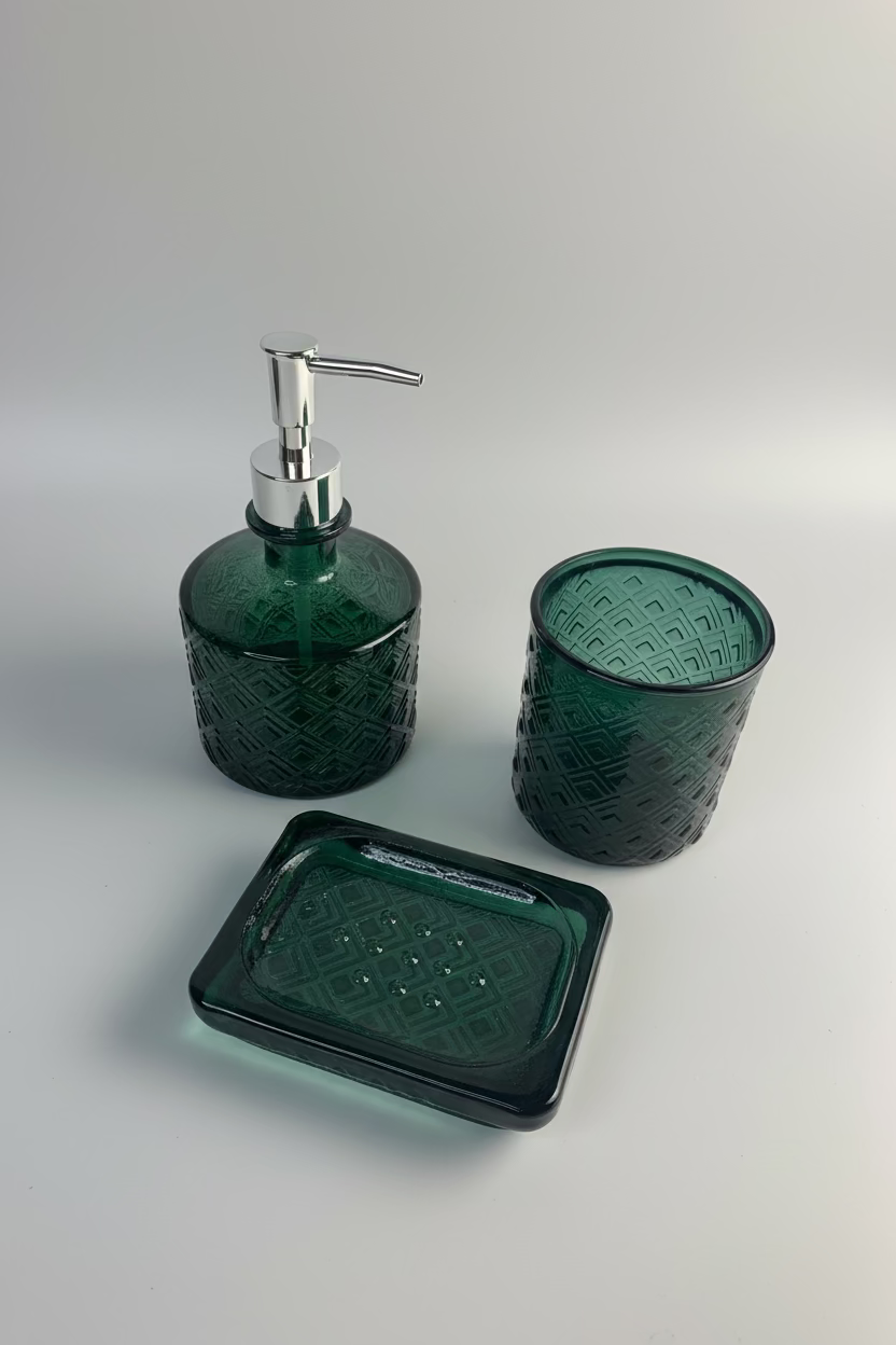 Three-piece dark green glass bathroom set with a pump dispenser, a cup, and a rectangular soap dish, all featuring a textured geometric pattern 