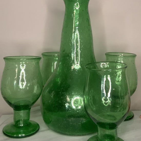A green recycled glass goblet or tumbler with a wide flared rim and a short stem.