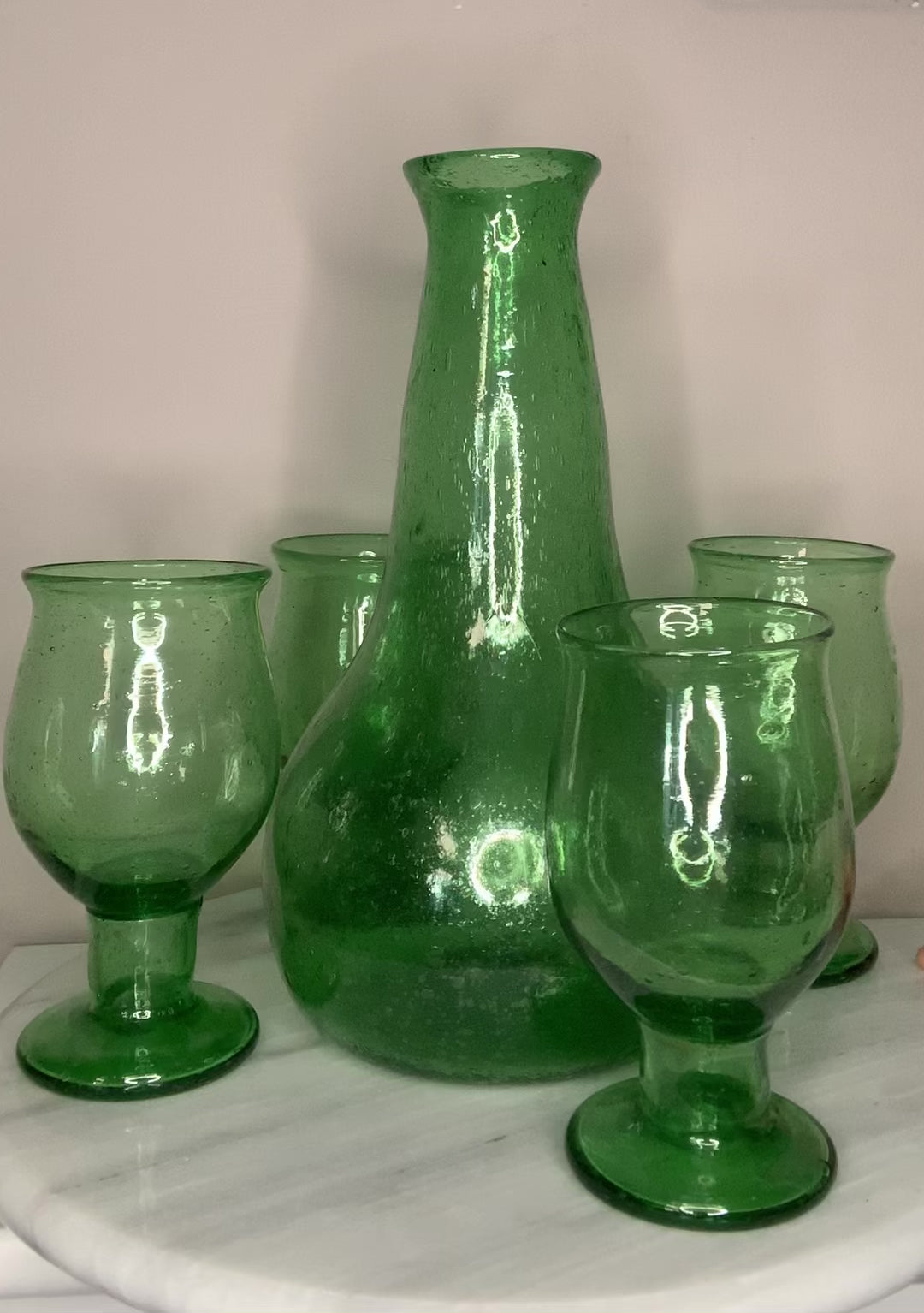 Emerald Green Bottle Decanter Carafe, hand-blown from recycled bubble glass with a characteristic pontil mark. Each piece features naturally occurring air bubbles throughout, a hallmark of the traditional glassblowing process. Beautiful as a standalone decorative object or paired with a set of recycled glasses.