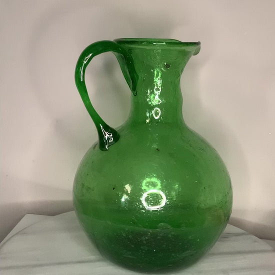 Hand-blown emerald green glass bottle decanter carafe with visible air bubbles throughout and a pontil mark, suitable for use as a vase or decorative piece.
