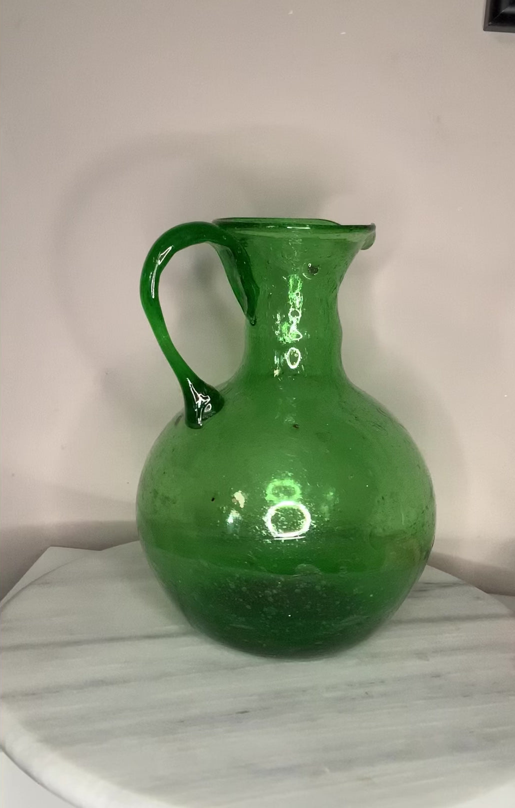 Hand-blown emerald green glass bottle decanter carafe with visible air bubbles throughout and a pontil mark, suitable for use as a vase or decorative piece.