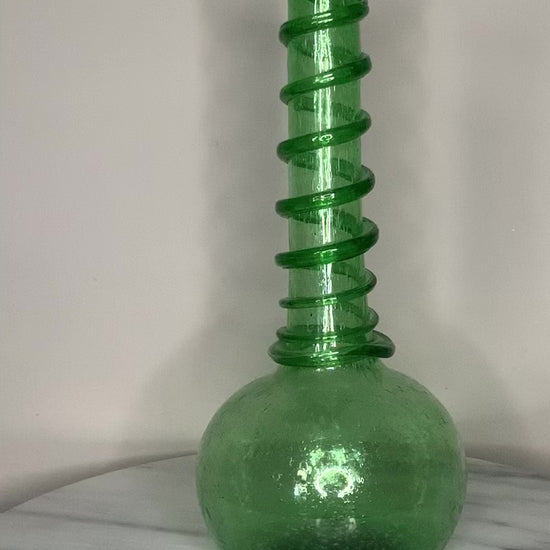 Hand-blown emerald green recycled glass bud vase with air bubbles throughout and a spiral decoration along the neck, finished with a pontil mark.