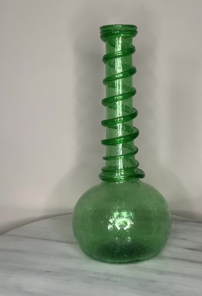 Hand-blown emerald green recycled glass bud vase with air bubbles throughout and a spiral decoration along the neck, finished with a pontil mark.