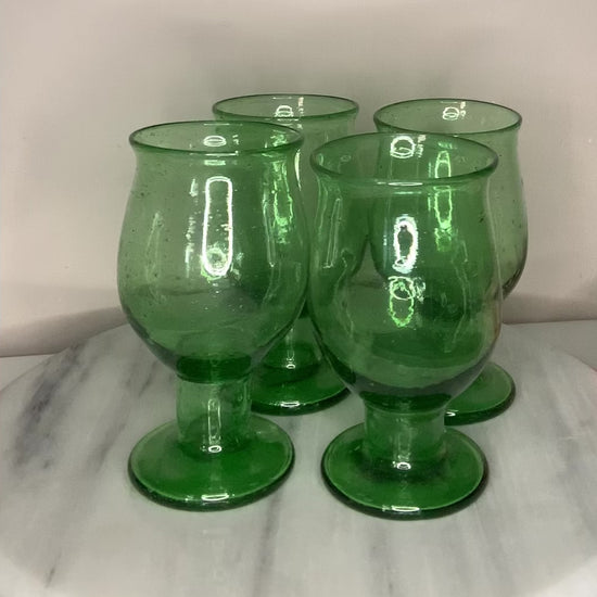 A green recycled glass goblet or tumbler with a wide flared rim and a short stem.