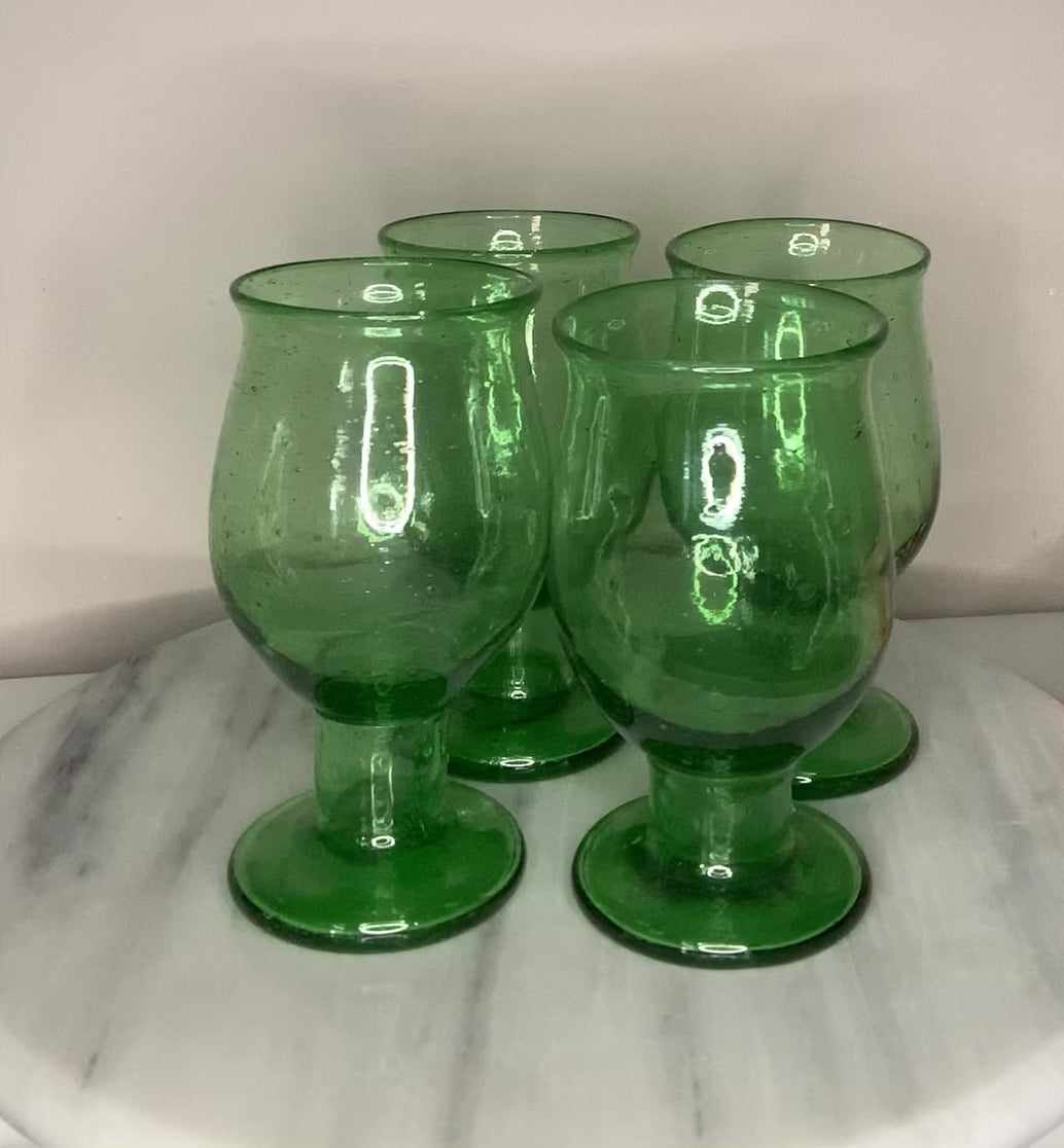A green recycled glass goblet or tumbler with a wide flared rim and a short stem.